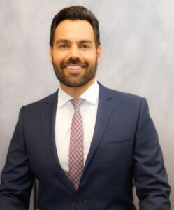 A man in suit and tie smiling for the camera.