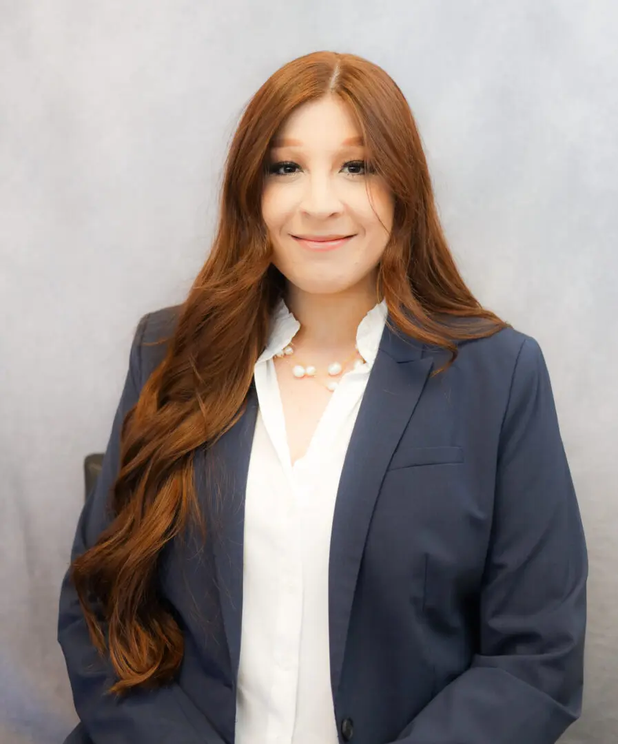 A woman with long red hair wearing a suit.